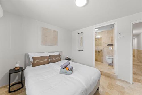 a white bedroom with a large bed and a bathroom at Caribe CBW in Willemstad