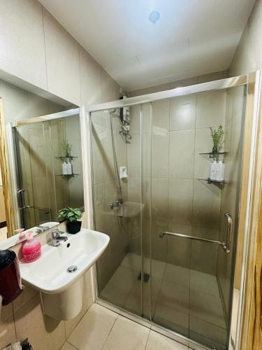a bathroom with a glass shower and a sink at Inspiria Cozy Condo in Cabaguio
