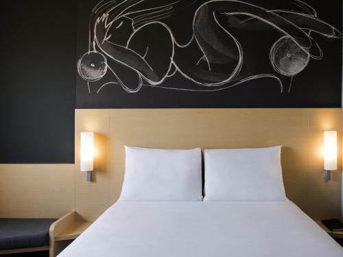 a bed with two white pillows in a room at Ibis Irapuato in Irapuato