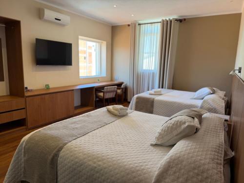a hotel room with two beds and a flat screen tv at Hotel Victoria Plaza in Tarija