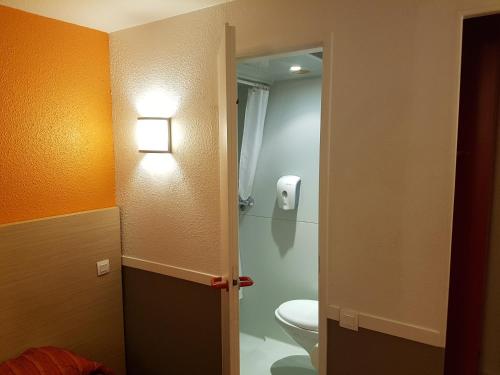 a bathroom with a toilet and a light on the wall at HECO Colmar Nord - ex Première Classe in Houssen