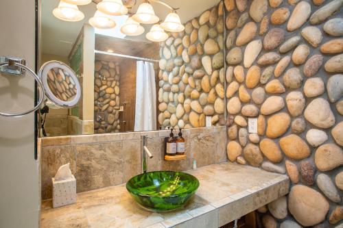 a bathroom with a stone wall with a sink and a mirror at Inn At Avila Beach in Avila Beach