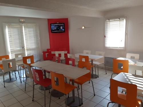 a dining room with tables and chairs and a tv at HECO Colmar Nord - ex Première Classe in Houssen