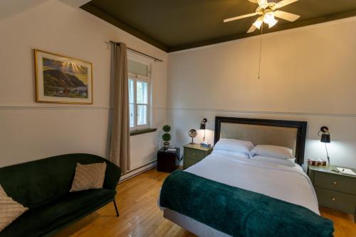a bedroom with a large bed and a chair at Aux petits oiseaux in Baie-Saint-Paul