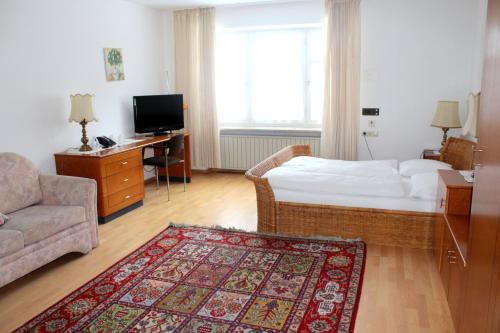 a hotel room with a bed and a couch and a desk at Villa am Park in Bad Tölz