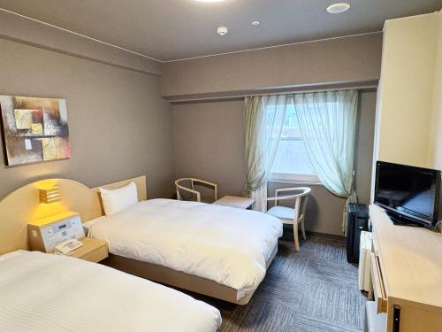 a hotel room with two beds and a television at Hotel Route-Inn Tokyo Asagaya in Tokyo