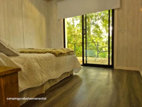 a bedroom with a bed and a sliding glass door at cabañasmanantialpanguipulli in Panguipulli
