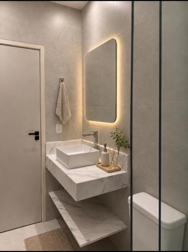 a bathroom with a sink and a mirror and a toilet at Casa Cerejeiras - Condomínio Privado in Bananeiras