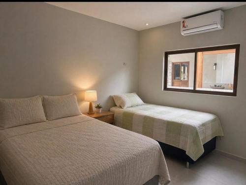 two beds in a room with a window and a bedskirts at Casa Cerejeiras - Condomínio Privado in Bananeiras