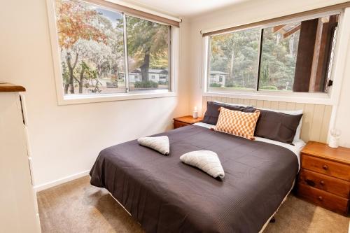 a bedroom with a large bed with two windows at Ovens River Retreat in Harrietville