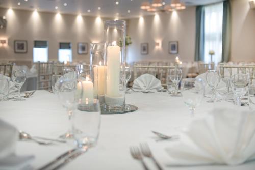 a table with glasses and candles in a room at Staverton Park Hotel & Golf Club in Daventry