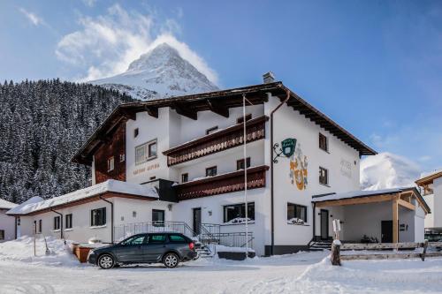 een gebouw met een auto in de sneeuw bij Hotel Alpina in Galtür