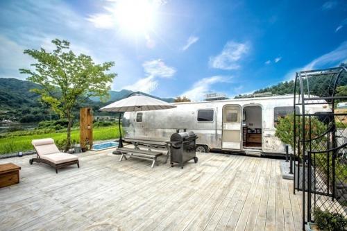 an rv parked on a deck with a picnic table and an umbrella at Out of Park in Chuncheon