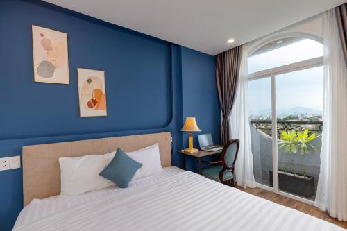 a bedroom with blue walls and a bed with a window at Fusia Hotel & Apartment in Danang