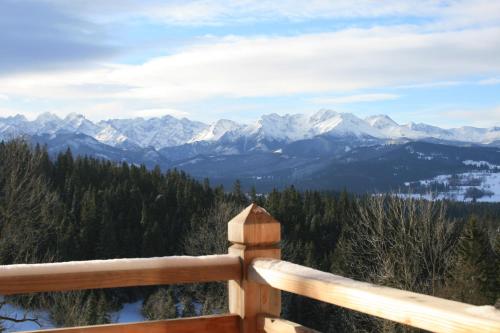 a view of the mountains from a wooden railing at udanypobyt Dom Forest Prestige House in Rzepiska