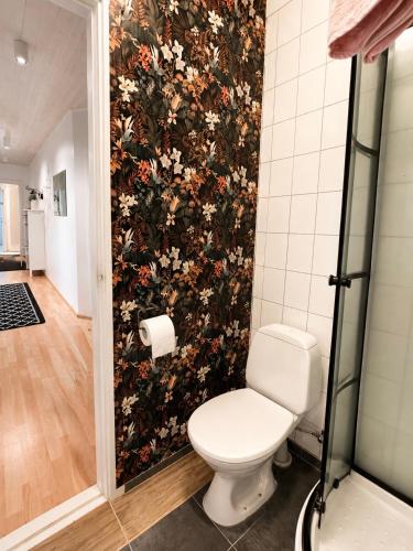 a bathroom with a toilet and a floral wall at Aurora Apartament in Borgarnes