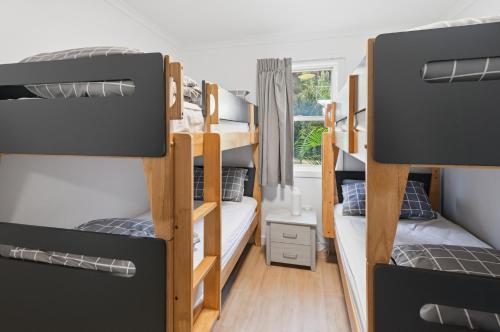 a dorm room with three bunk beds and a window at Villa 3 Beach Front Tangalooma in Tangalooma