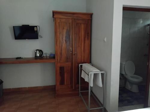 a bathroom with a toilet and a wooden cabinet at Griya Bun Sari in Sukawati