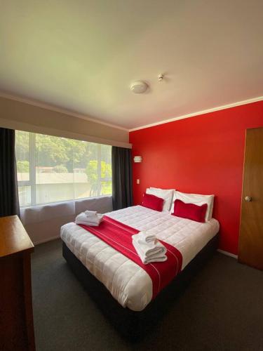 a bedroom with a large bed with a red wall at Waitangi Beach House in Paihia