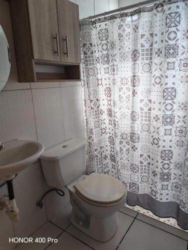 a bathroom with a toilet and a sink and a shower curtain at ZU Apartamentos in Los Algarrobos