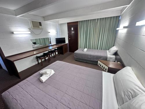 a hotel room with a bed and a desk at Charles Sturt Motor Inn in West Wyalong