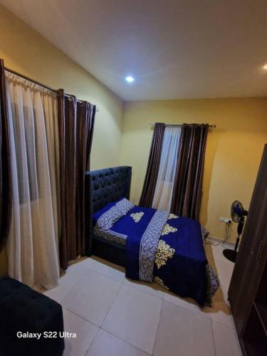 a bedroom with a blue bed and curtains at Nest Nova in Alagbado