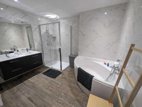 a bathroom with a tub and a sink and a shower at L'ecole buissonnière in Riaucourt