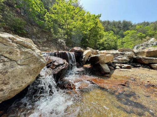 a waterfall on a rocky hill with trees in the background at Yangyang Dalpaengi Pension in Yangyang