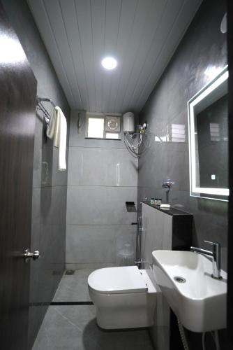 a bathroom with a white toilet and a sink at TheCloud Hotel in Nizāmābād