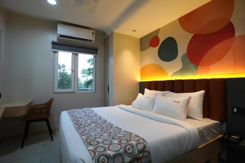 a bedroom with a bed with a painting on the wall at TheCloud Hotel in Nizāmābād