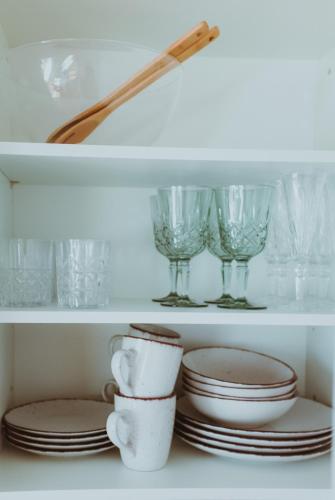 a white shelf with plates and glasses on it at RheinStrand, wunderschöne, renovierte Wohnung in Dormagen