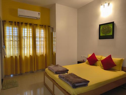 a bedroom with a bed with red and yellow pillows at Athreyas@60/A in Mysore