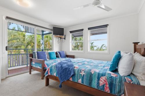 a bedroom with a bed with a blue bedspread and windows at Villa 31 Tangalooma Beach Front in Tangalooma
