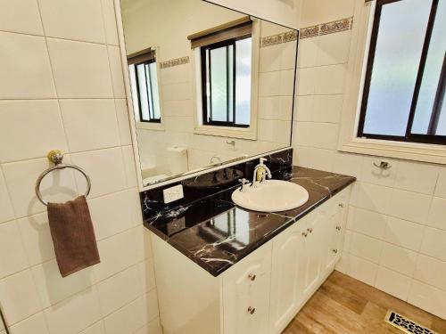 a bathroom with a sink and a mirror at Wombat Cottage Albury in Albury