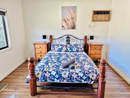 a bedroom with a bed with a blue floral bedspread at Wombat Cottage Albury in Albury