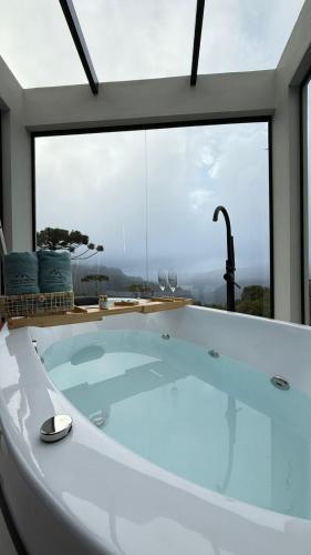a bath tub in a room with a large window at Altos do Perito Cabanas in Alfredo Wagner
