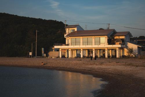 a house sitting on the beach next to a body of water at TORIKKA Stay -ビーチに建つ貸別荘- in Sumoto