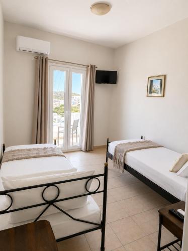 two beds in a room with a window at Aurelia Rooms in Ios Chora