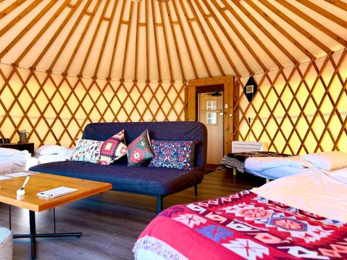 a yurt with a couch and a bed and a table at Minamiaso BlueBeeGarden in Minami Aso