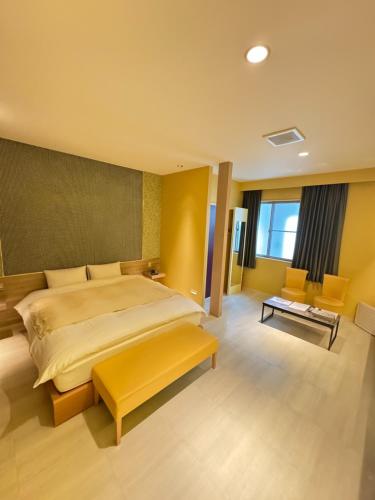 a large bedroom with a large bed and a yellow bench at Hotel JOYCE in Saijō-chō