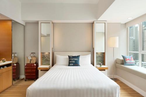 a bedroom with a large white bed and two windows at Jen Hong Kong by Shangri-La in Hong Kong