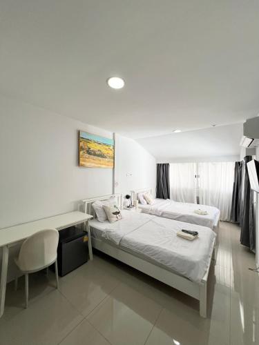 a room with two beds and a desk and a table at Tiger Homestay in Bangkok
