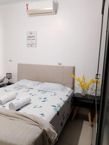 a bed in a bedroom with a white wall at Casa Grande com 4 camas, 2 Quartos com AR CONDICIONADO nos dois quartos in Juazeiro do Norte