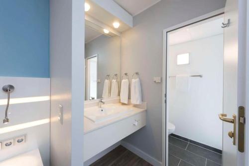 a bathroom with a sink and a toilet and a mirror at Peine Salzgitter Hotel by Belvilla in Peine