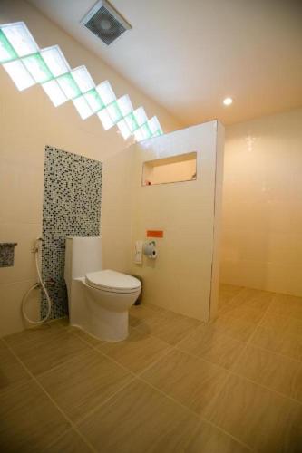 a bathroom with a toilet in a room with a skylight at Pharadhevi in Ban Dung