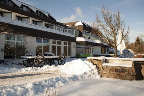 a snow covered yard in front of a building at H+ Hotel Willingen in Willingen