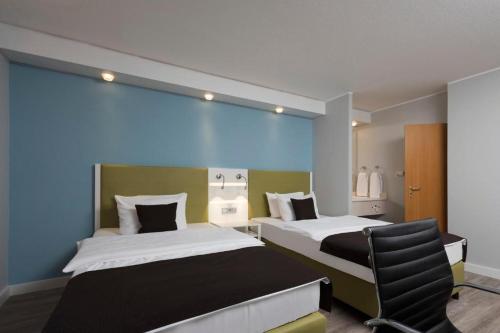 a hotel room with two beds and a chair at Peine Salzgitter Hotel by Belvilla in Peine