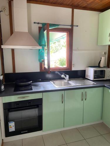 a kitchen with a sink and a microwave at La Palmeraie in Le Moule