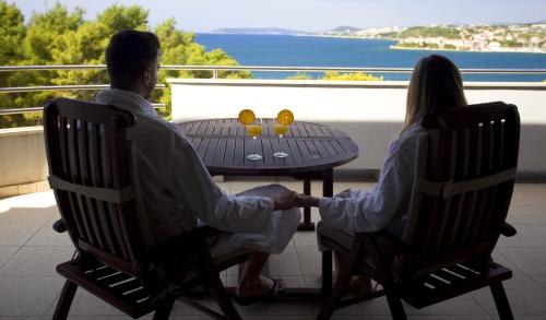 a man and a woman sitting at a table on a balcony at Hotel Eden in Podstrana