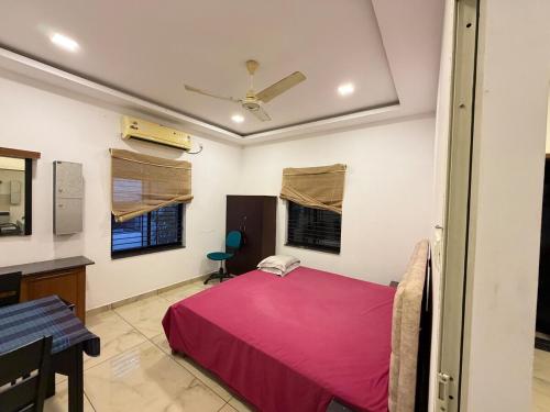 a bedroom with a pink bed and a desk at Triple A Gardens in Kollam